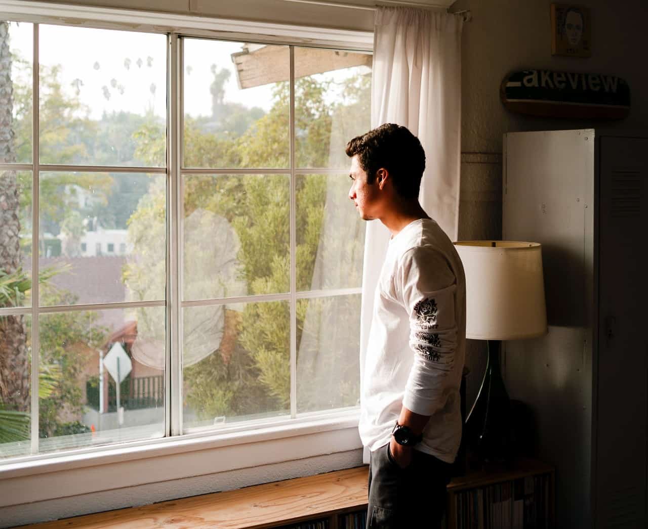 A man looking out a window with a thoughtful look on his face.