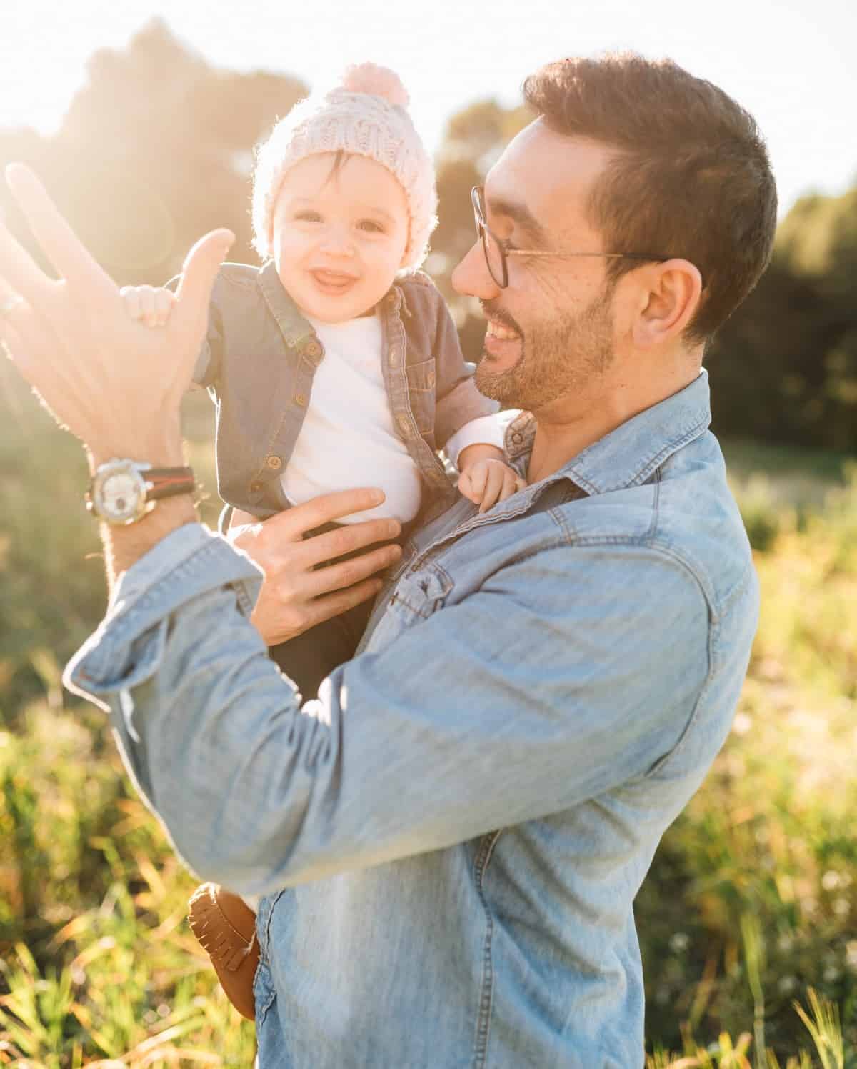 A dad holding his daughter outside.
