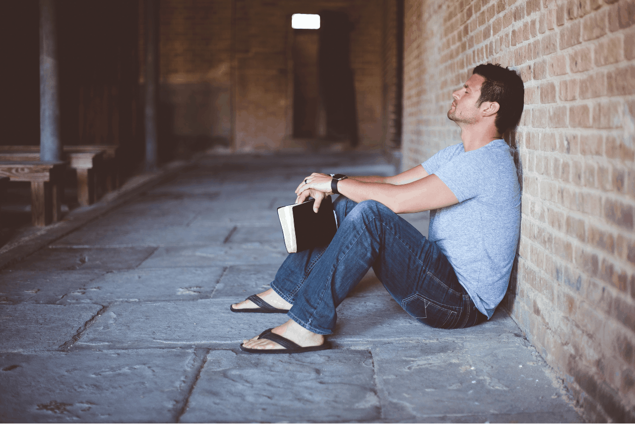 A man sitting on the ground with a Bible.