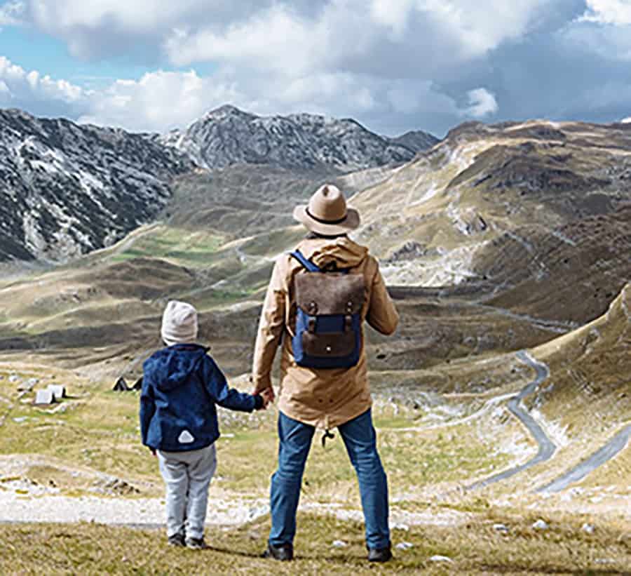 Father and son holding hands facing a mountain range