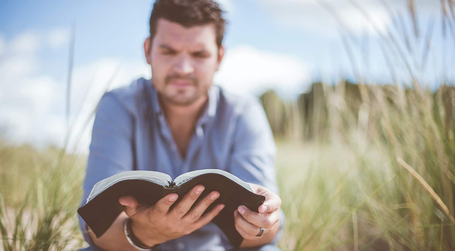 Man reading bible outside.