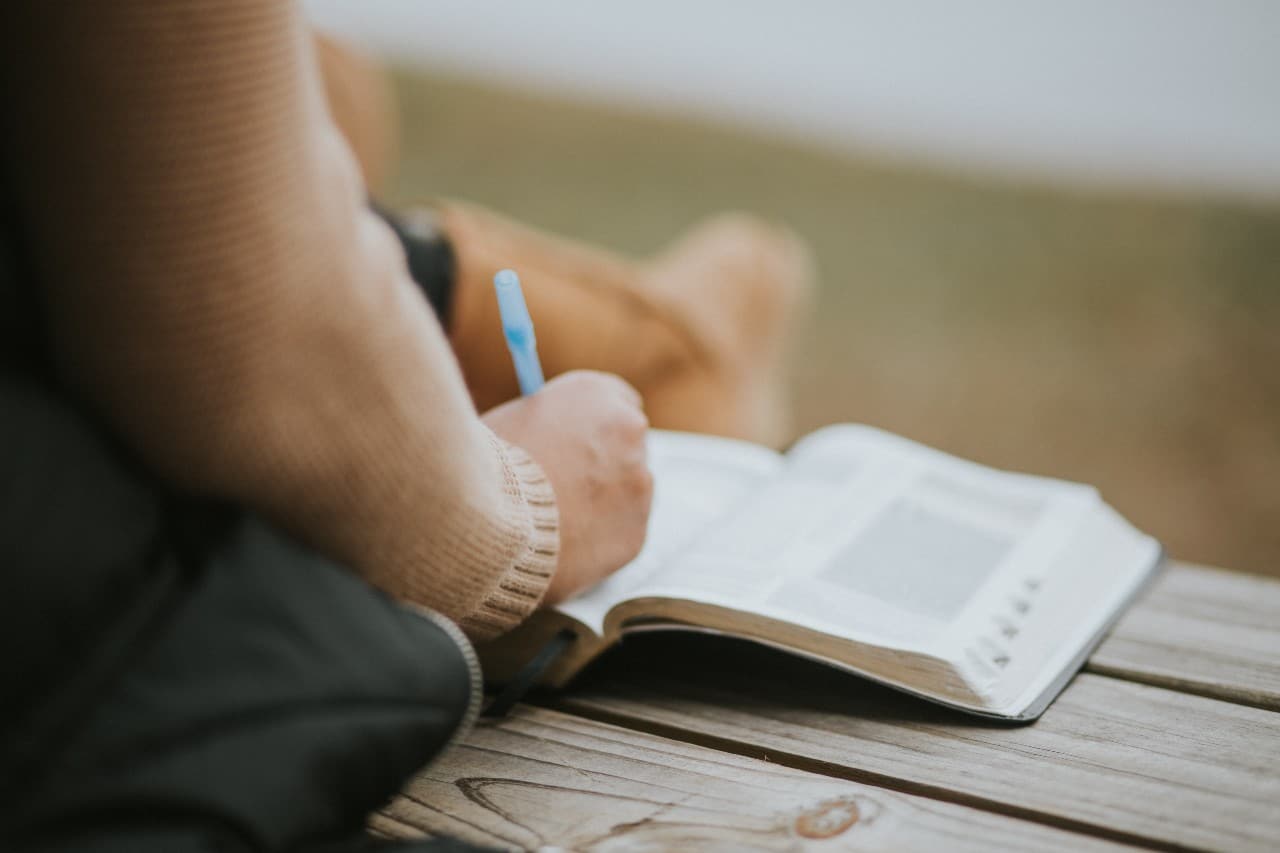 A girl holding a pen with an open Bible.