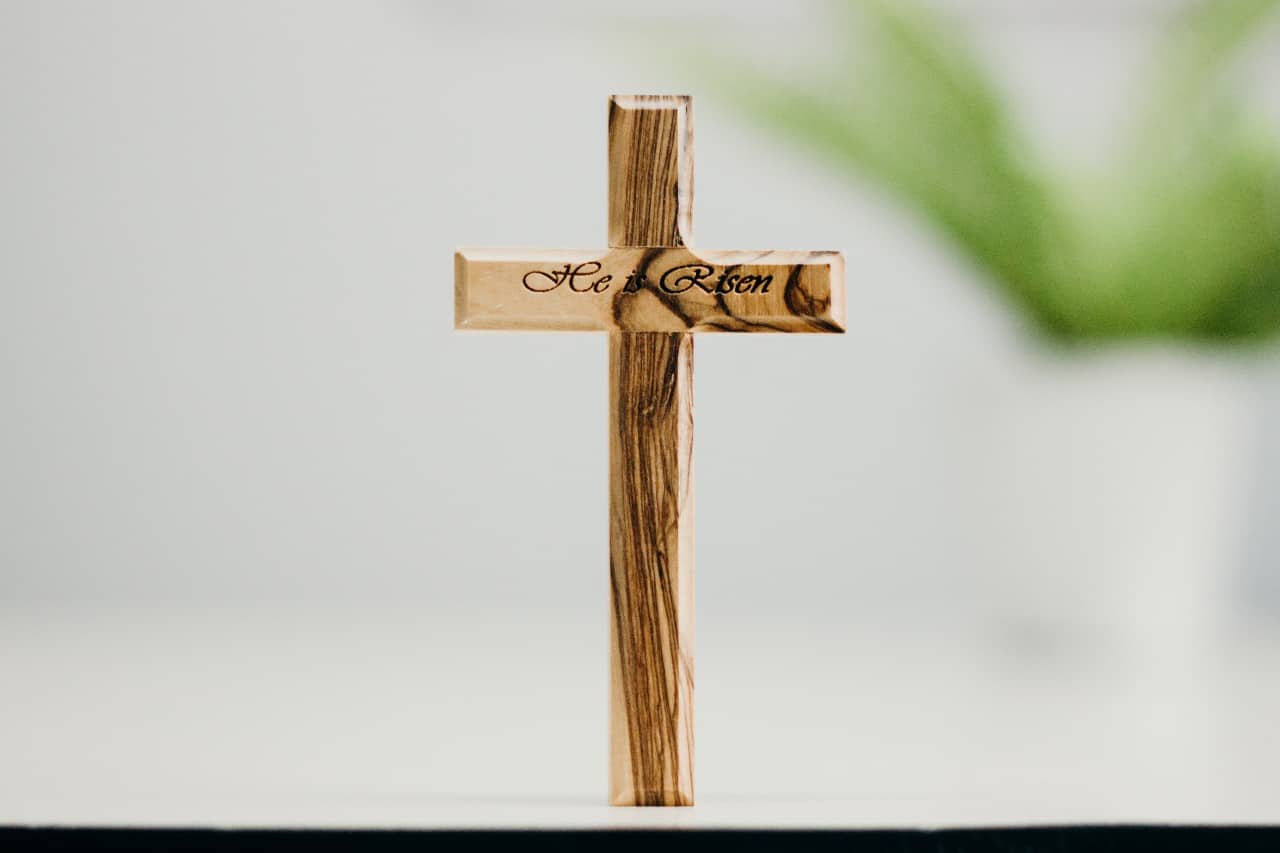 A wooden cross with the words "He is risen".