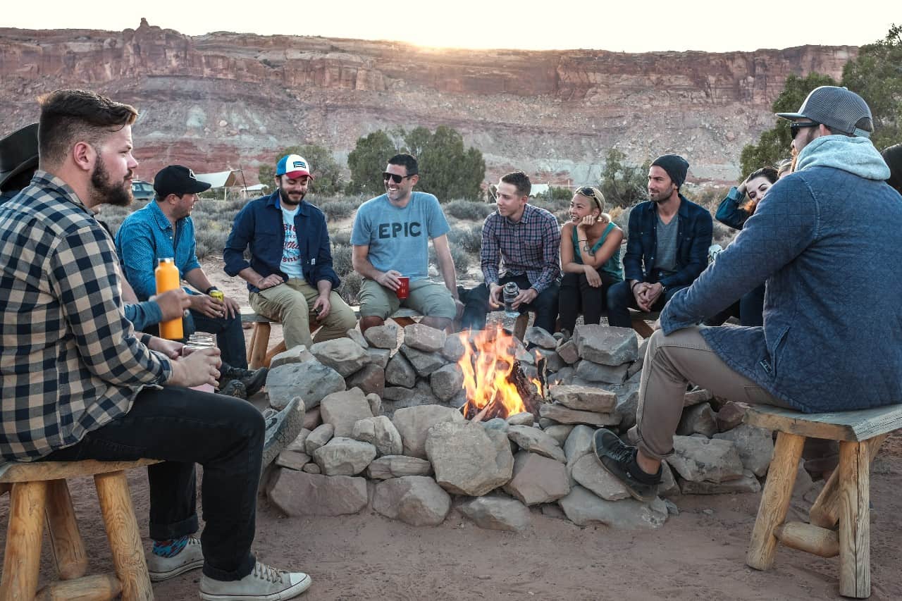 A group of friends sitting outside around a fire pit.