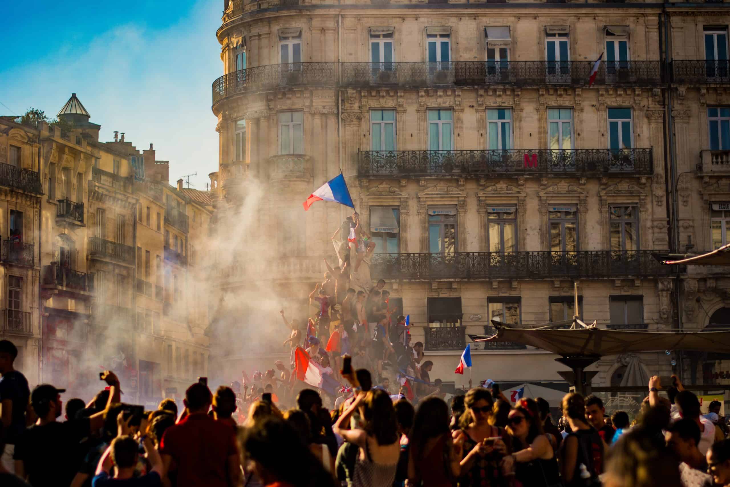 French revolution celebration with flags, smoke and in front of buildings