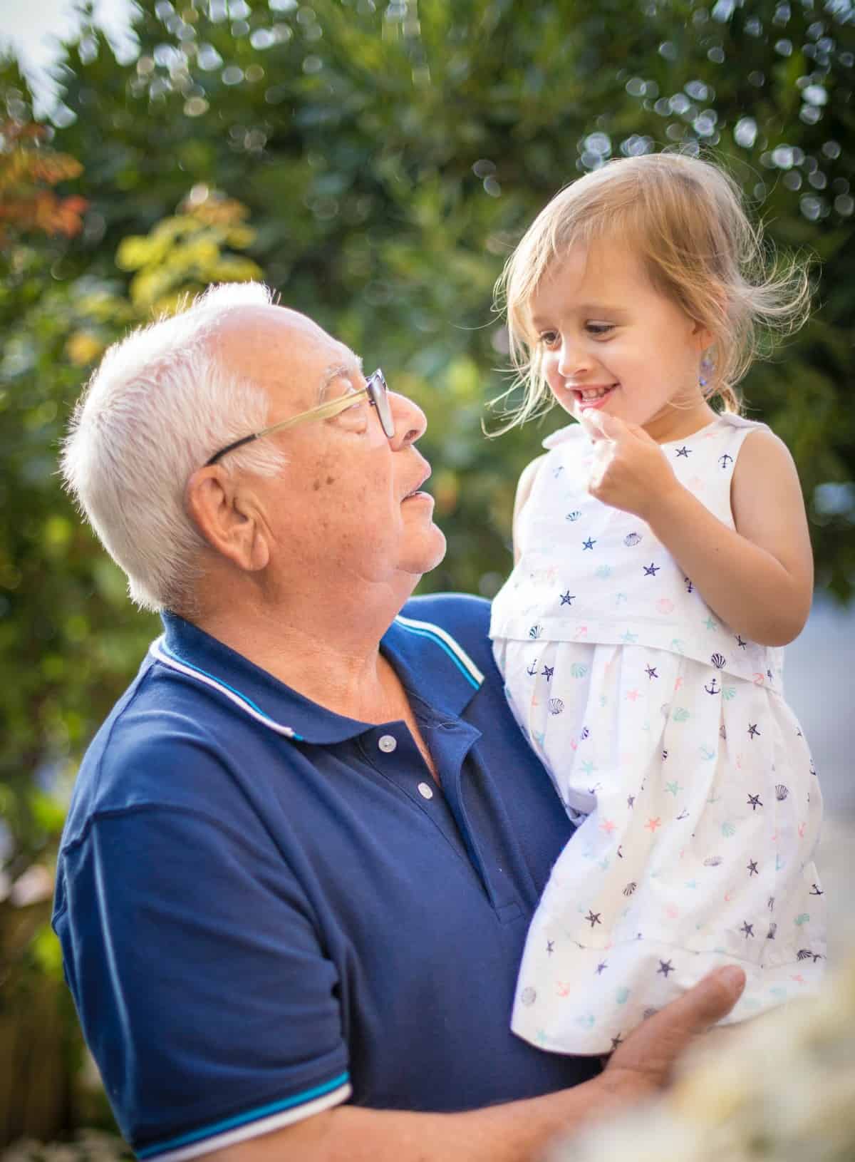 A grandfather holding his young granddaughter.