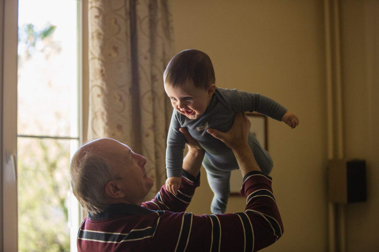 A grandpa holding his grandson in the air.
