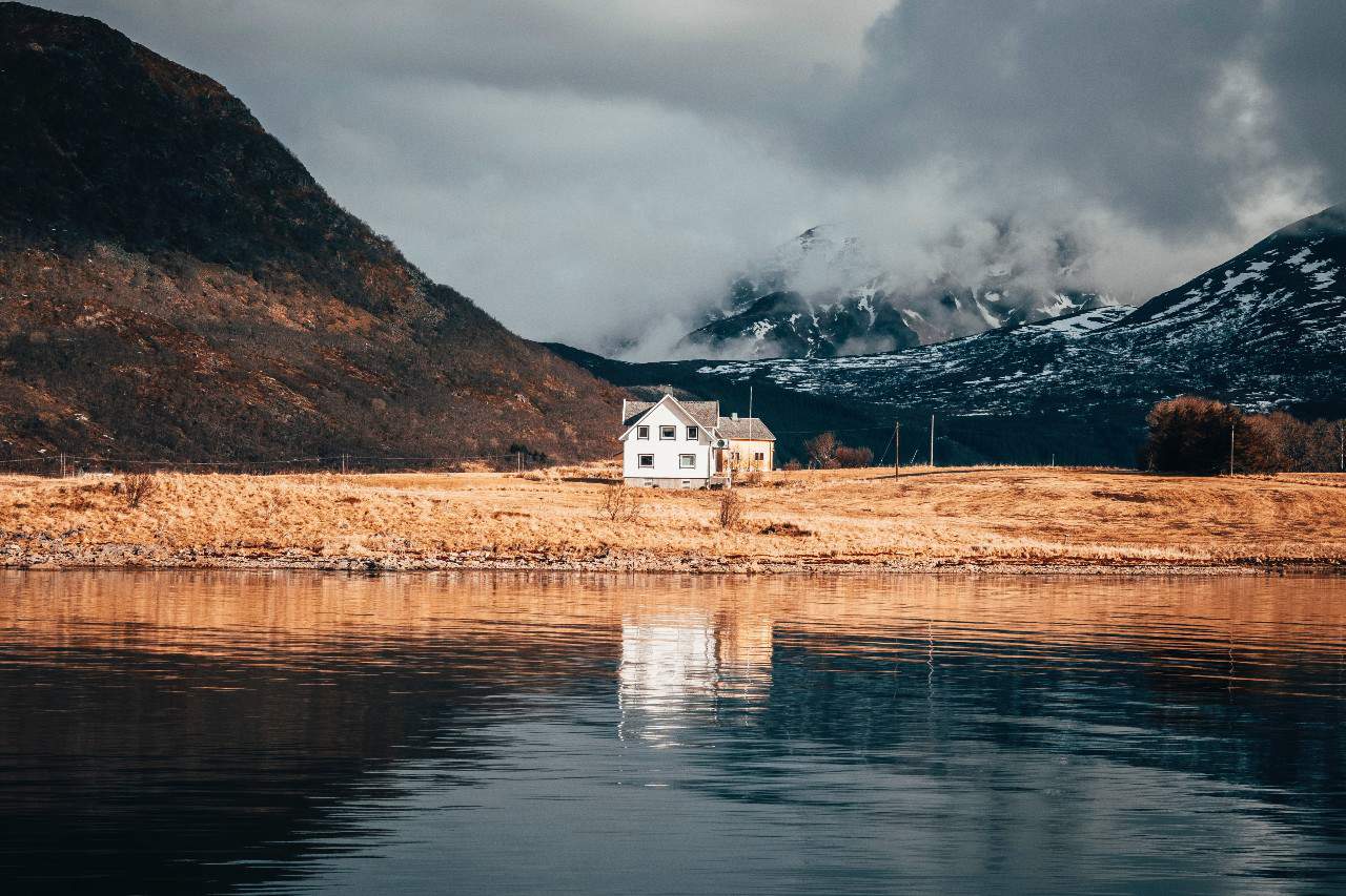 A house by a lake with mountains on either side.