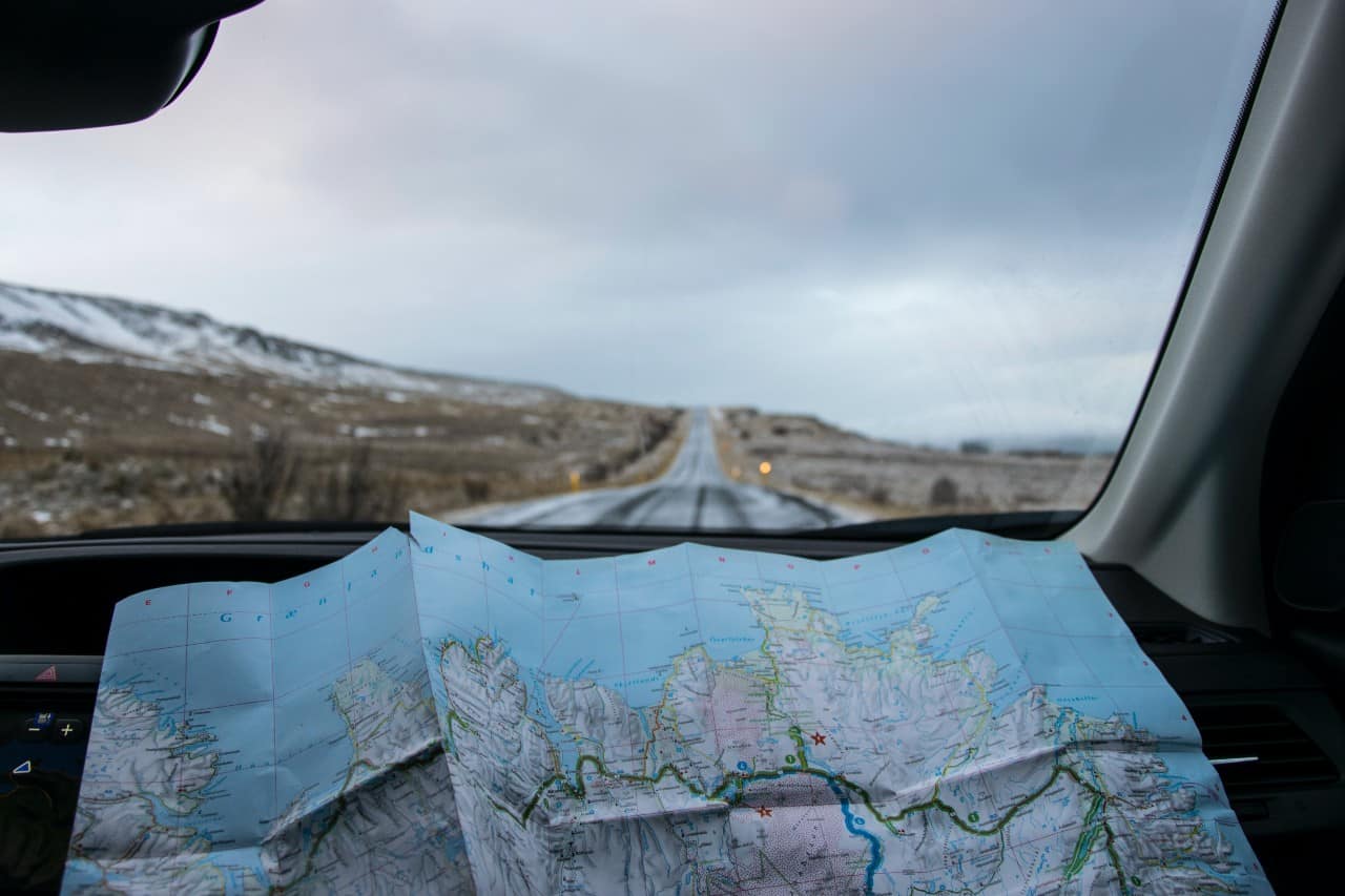 view from the inside of a car looking out at the road ahead with an open map.