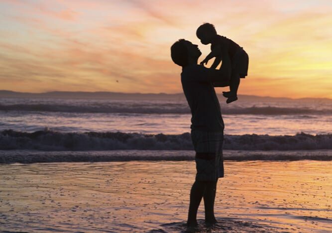 Father holding child on the beach