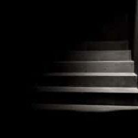 A dark staircase with a small amount of light illuminating part of the stairs.