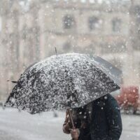 An image of a man holding an umbrella during a snow storm.