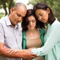 dad-and-mom-with-teen-girl-praying