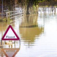 Flooded road and warning sign, half submerged