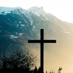 A photo of a wooden cross in front of a mountain.