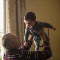 A grandpa holding his grandson in the air.