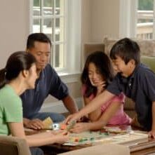 Family at table playing board game