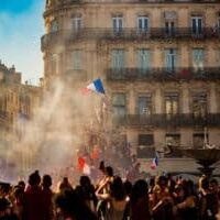 French revolution celebration with flags, smoke and in front of buildings